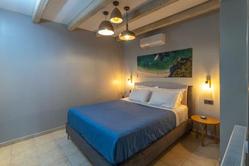 a bedroom with a bed with blue sheets and a table at Apeiron Villas - Olive Forest Apartment in Kefallonia