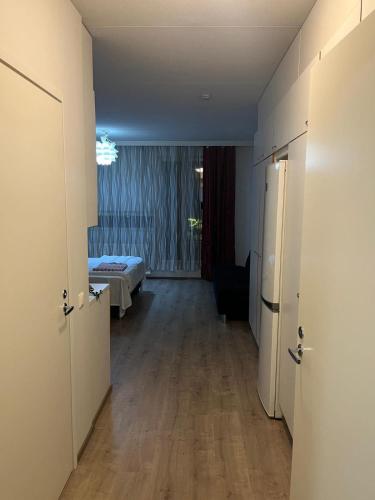 a hallway with a room with a bed and a refrigerator at Air conditioned Apartment in Espoo