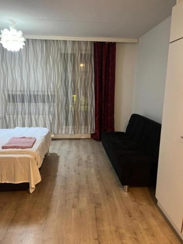 a bedroom with a bed and a couch and a window at Air conditioned Apartment in Espoo