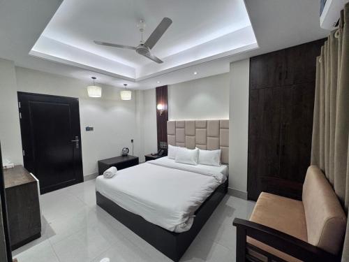 a bedroom with a large white bed and a couch at Grand Khalifa Hotel Hamama in Sylhet
