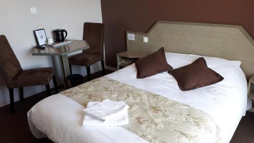 a hotel room with a bed and a table and chairs at Logis La Rose Des Vents in Volvic