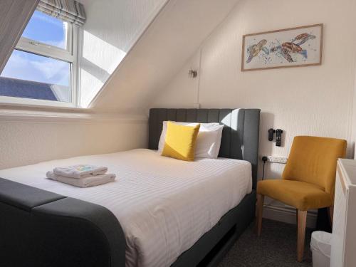 a bedroom with a bed with a chair and a window at Gumfreston Guest House in Tenby