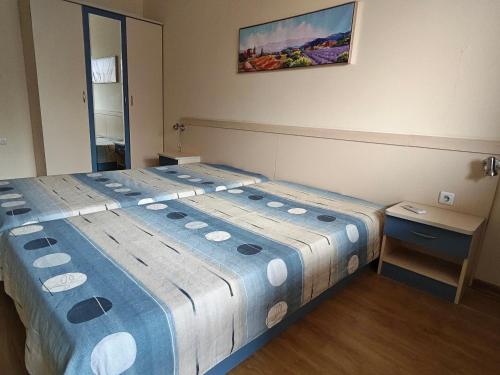 a bedroom with a bed with a blue and white blanket at HostEx Trinity Apartment in Stara Zagora