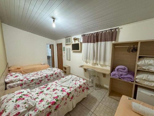 a room with two beds and a desk in it at Pousada Jubaia in Bonito