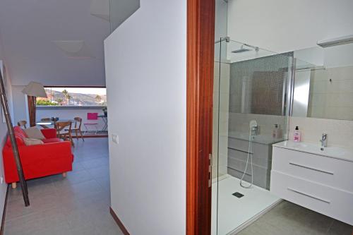 a bathroom with a glass shower and a red couch at El Baladero in Telde