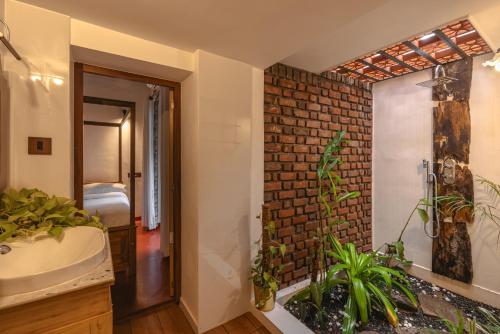 a bathroom with a sink and a brick wall at The Oneness Living- Seasonal Heritage stay with Tholpaavakoothu nights in Pazhayannūr