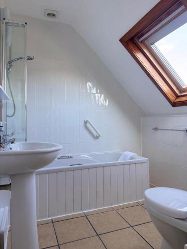 a bathroom with a tub and a sink and a toilet at Gumfreston Guest House in Tenby
