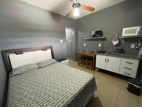 a bedroom with a bed and a kitchen with a ceiling fan at kit net central 2 in Serra Negra