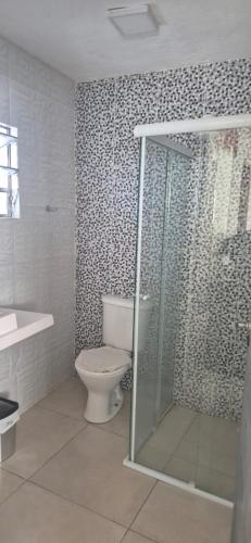 a bathroom with a toilet and a glass shower at Cantinho de conforto in Mongaguá