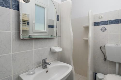 a white bathroom with a sink and a mirror at Apollon Rooms 2 in Pollonia
