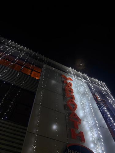 a building with a neon sign on it at night at MADAVATH RESIDENCY in Kenichira
