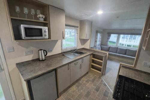 a small kitchen with a sink and a microwave at Reeva's Resort at Littlesea Holiday Park, Weymouth in Wyke Regis