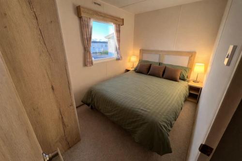 a small bedroom with a bed and a window at Reeva's Resort at Littlesea Holiday Park, Weymouth in Wyke Regis