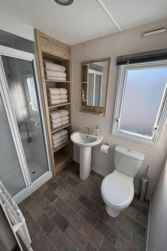 a bathroom with a toilet and a sink and a shower at Reeva's Resort at Littlesea Holiday Park, Weymouth in Wyke Regis