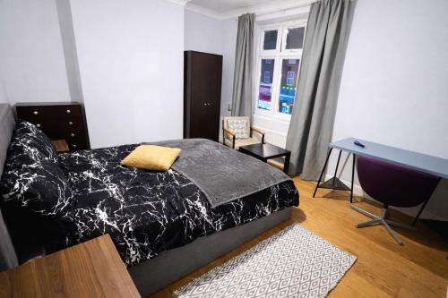 a bedroom with a bed and a desk and a window at Midnight Horizon - shared bathroom in Ponders End
