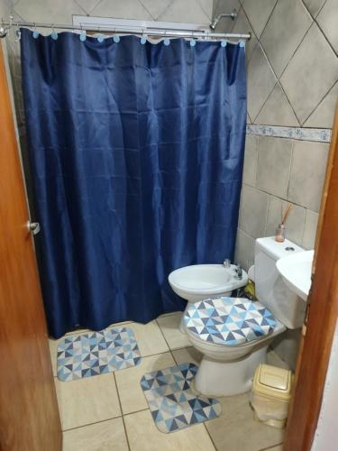 a bathroom with a blue shower curtain and a toilet at DepartamentosJYM in Federación