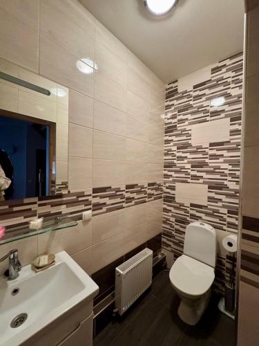 a bathroom with a white toilet and a sink at Saules home Jomas - early check in, late check out in Jūrmala