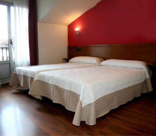 a bedroom with a large bed with a red wall at Hotel Virgen de Covadonga in Cangas de Onís