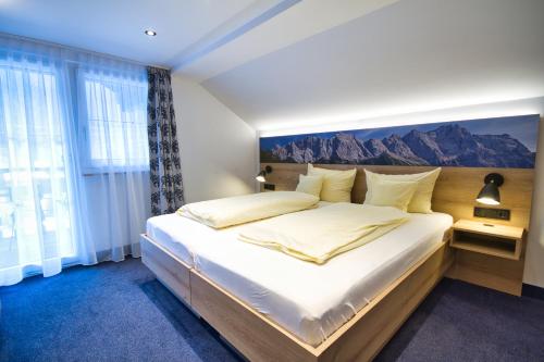 a bedroom with a large bed with a painting on the wall at Zum Franziskaner in Grainau