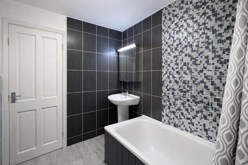 a bathroom with a sink and a tub and a toilet at Midnight Horizon - shared bathroom in Ponders End