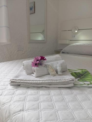 a white bed with towels and a flower on it at B&B Rena Majore con piscina privata! in Rena Majore