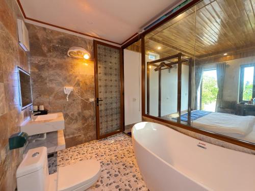 a bathroom with a tub and a toilet and a bed at Senna Garden Homestay in Xuân Sơn
