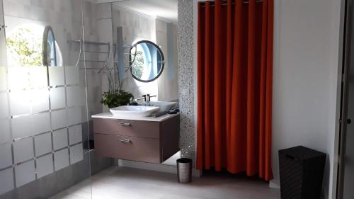 a bathroom with a sink and a red shower curtain at CAP COULEURS Guadeloupe in Lamentin