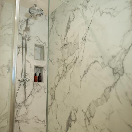 a bathroom with a shower with a white marble wall at River View Cottages in Annan