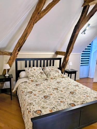 a bedroom with a bed with a comforter and two tables at Maisons de campagne. Gîte vert. in Brigné