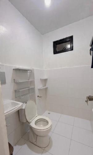 a white bathroom with a toilet and a sink at Aey Mabini Homestay in Mabini