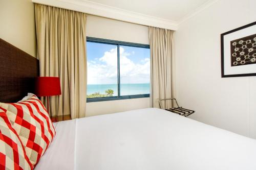 a bedroom with a large bed and a large window at Mantra on The Esplanade in Darwin