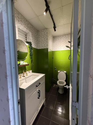 a green bathroom with a sink and a toilet at 221B Baker in Ấp Phú Thọ