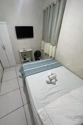 a bedroom with two beds and a flat screen tv at Suite in Arraial do Cabo in Arraial do Cabo