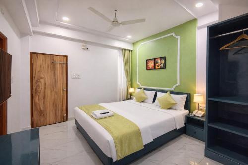 a bedroom with a large bed with green walls at Hotel The Hood in Nagpur