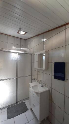 a white bathroom with a sink and a mirror at Morada Caminho do Mar in Praia do Rosa