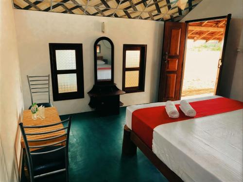 a bedroom with a bed and a table and a mirror at Sunrich Beach Resort in Ilandaiyadi