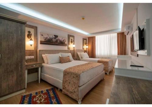 a hotel room with two beds and a television at Elit Lara Otel in Salihli
