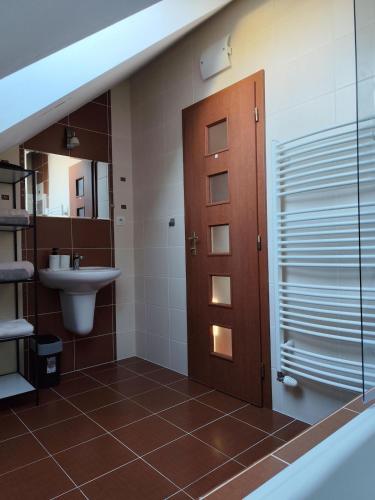a bathroom with a sink and a toilet and a door at Rooftop Apartment in Šamorín