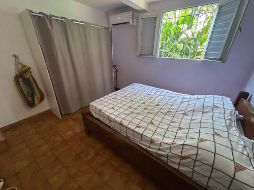 a small bedroom with a bed and a window at Kay Nono in Rivière-Salée
