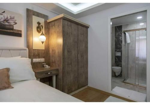 a bedroom with a bed and a wooden cabinet at Elit Lara Otel in Salihli