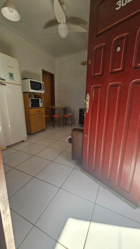 a room with a red door and a kitchen at Tranquilidade a 4 minutos da praia - Com Estacionamento Rotativo in Tramandaí