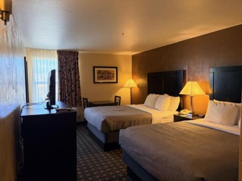 a hotel room with two beds and a desk at Quality Inn Zion Park Area in Hurricane