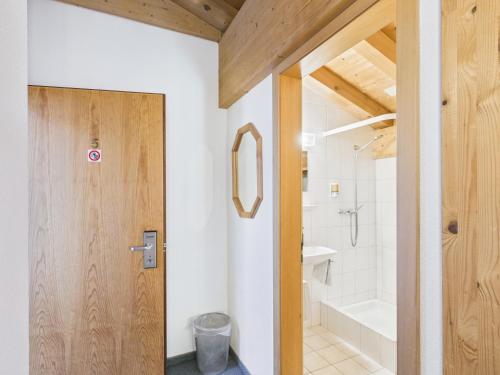 a bathroom with a wooden door and a bath tub at Hotel Wildbach Brienz - Self Check-in in Brienz