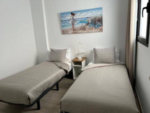 a room with two beds and a painting on the wall at Arguineguín sol y playa in Arguineguín