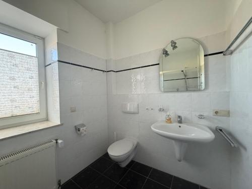 a white bathroom with a toilet and a sink at Wiehengebirgs Fernblick App 2 in Bad Essen