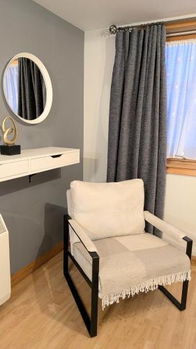 a chair in front of a window with a mirror at One bedroom self-contained accommodation in Lerwick