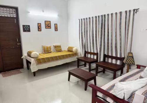 a living room with a bed and two chairs at Kelly cottages in Warangal