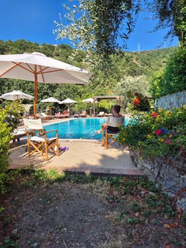 a person sitting in a chair next to a swimming pool at Borgo San Francesco in Gioiosa Marea