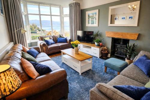 a living room with couches and a television and a fireplace at Bryn Gwyn, Sleeps 8, Sea Views, Borth y Gest in Porthmadog