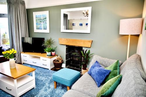 a living room with a couch and a fireplace at Bryn Gwyn, Sleeps 8, Sea Views, Borth y Gest in Porthmadog